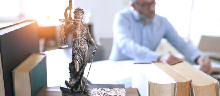 Justitia als Statue auf Bücherstapel