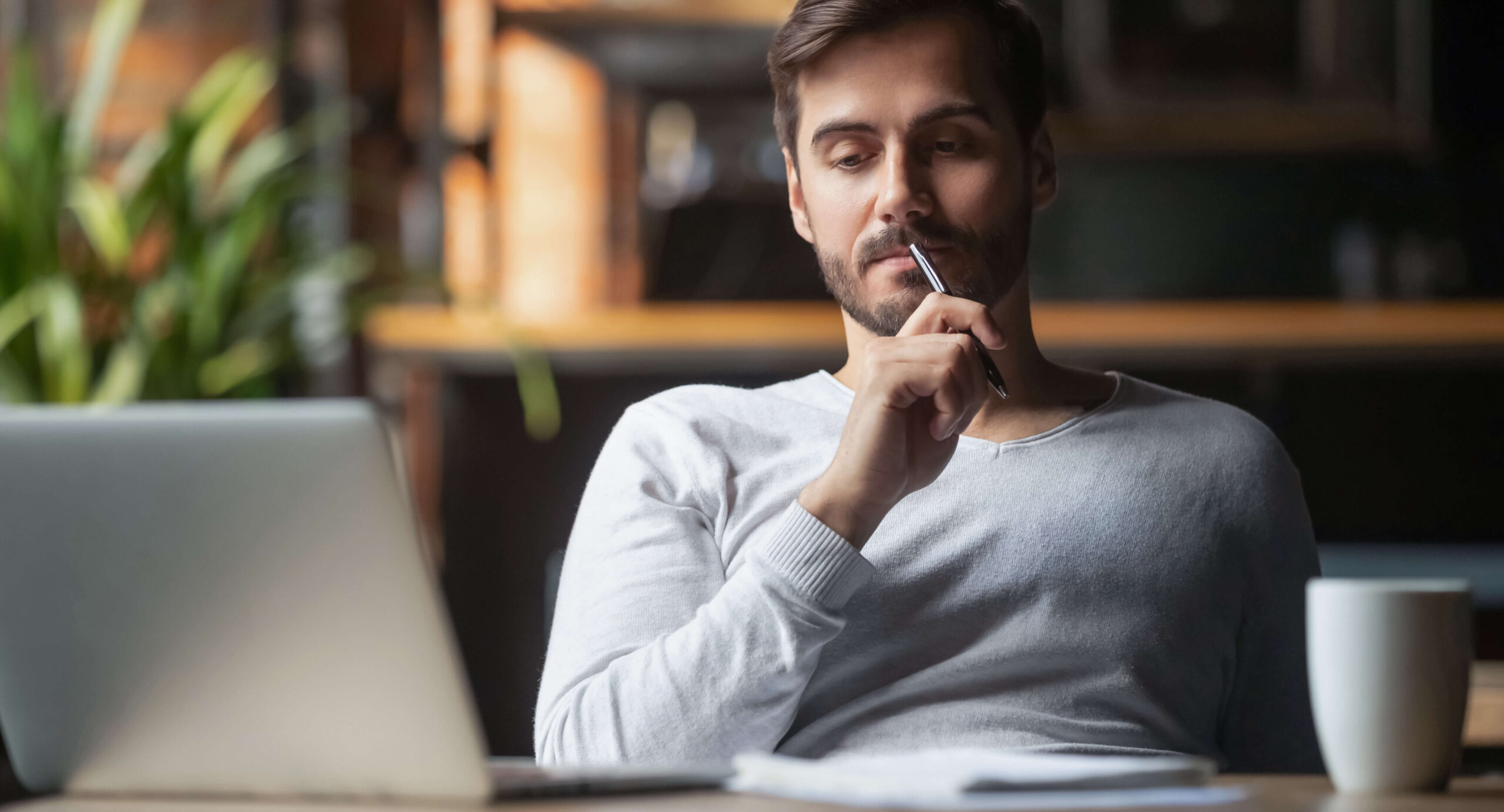 Nachdenklicher Mann arbeitet am Laptop
